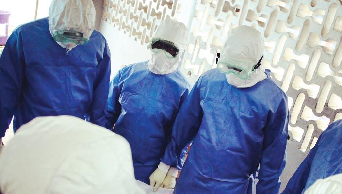 4 researchers wearing blue PPE and goggles