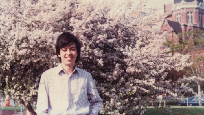 Chien-Jen Chen stands in front of a tree in bloom with the Hopkins dome in the background.