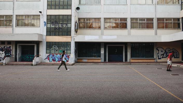 Image of refugees playing cricket in an abandoned school yard