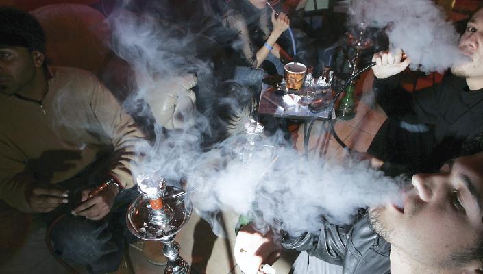 A group of young adults smoke in a hookah lounge. 