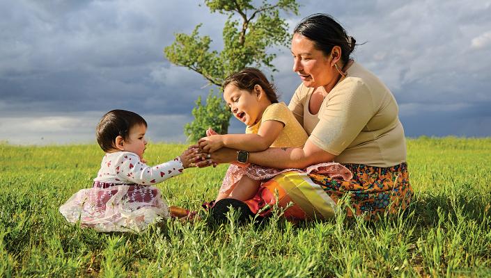 Red Lake Band of Chippewa  member Vernelle Lussier sits with daughters Brielle (left) and Zoie Chaboyea beside Red Lake in Minnesota in June 2022.