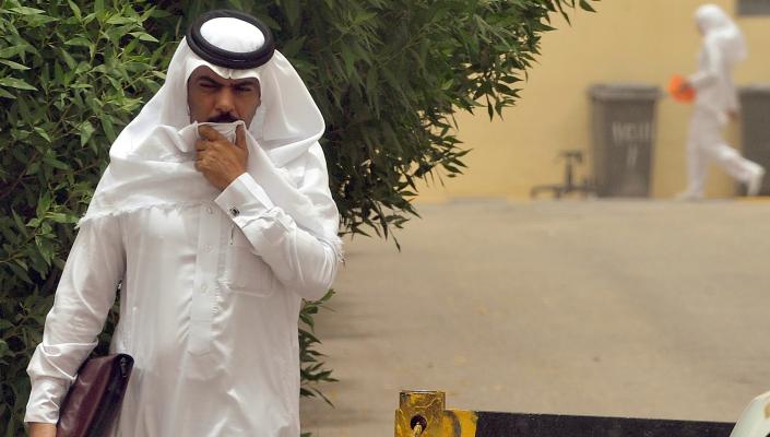 A Saudi man covers his mouth while walking down the street