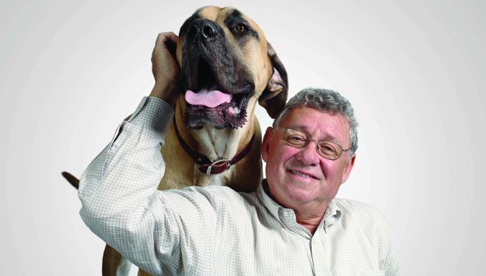 Allen Goldberg pets a big dog with its tongue out