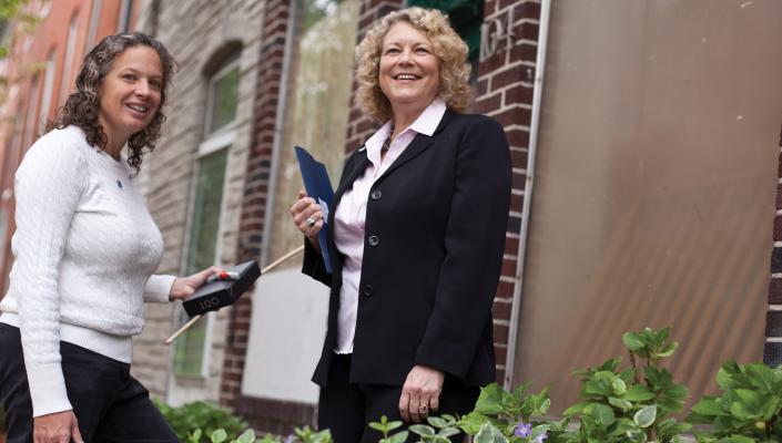 Wendy Shields and Andrea Gielen stand at the entrance to a rowhome in Baltimore