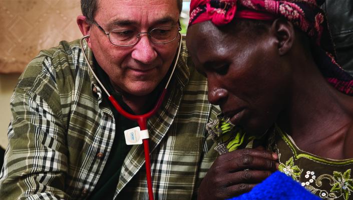 Philip Thuma listens to a man's lungs with a stethoscope