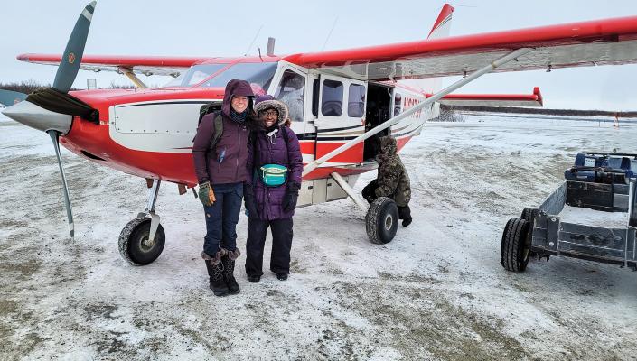 Mary McQuilkin and Bionca Davis in front of a plane in Alaska.