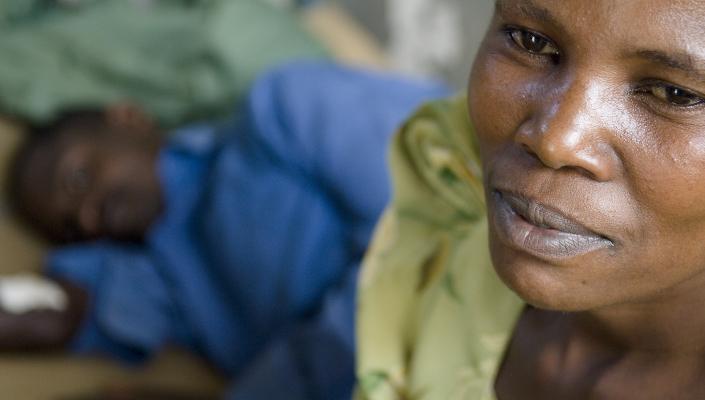 A Ugandan woman sits with a patient at a clinic run by the Rakai Health Sciences Program