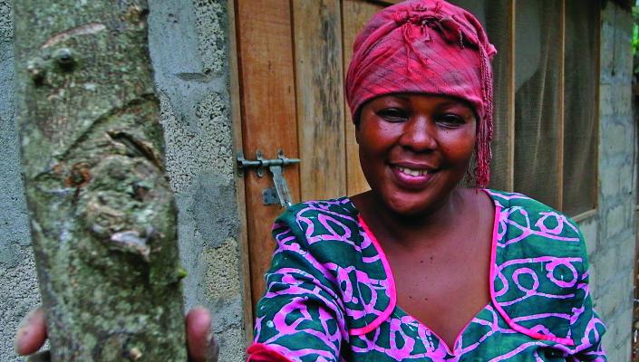 A Tanzanian woman in a colorful pink headscarf and blue and pink dress