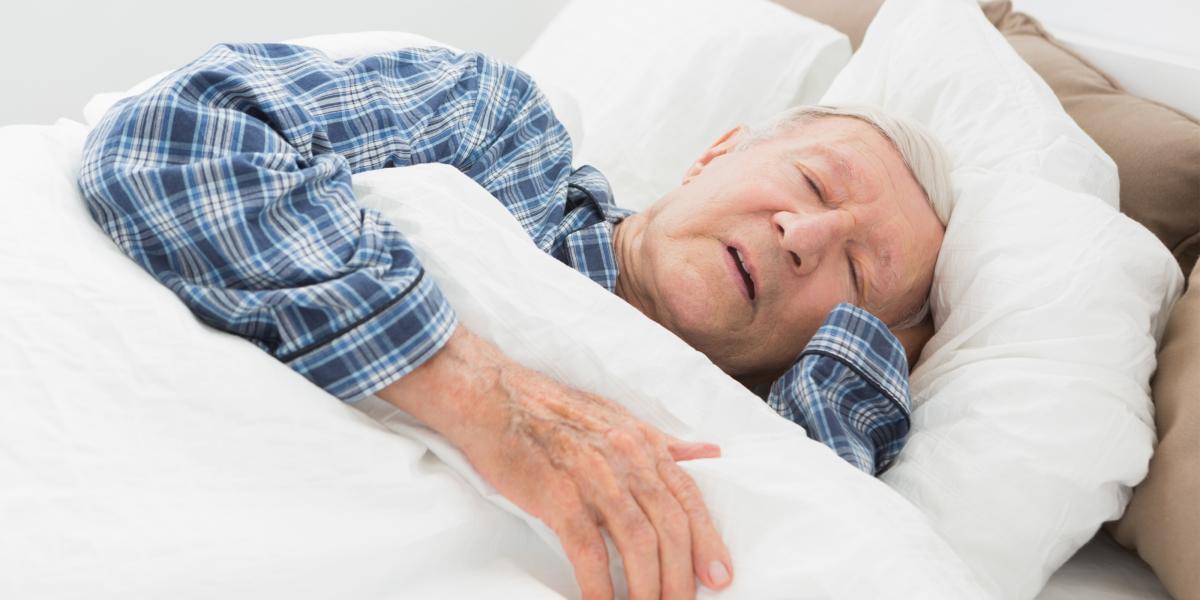 an older adult man asleep with one hand under his head