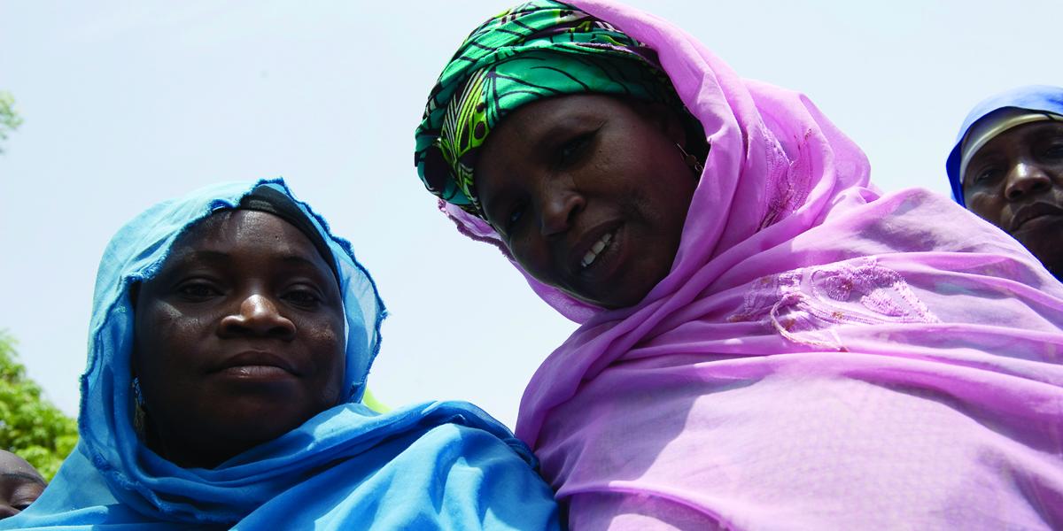 2 Nigerian women, one in a blue scarf and the other in pink