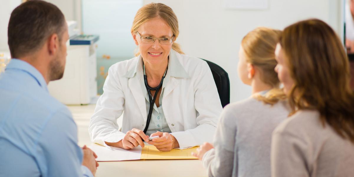 a female pediatrician talks with parents and their young daughter