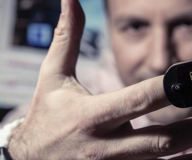 closeup of a man's hand with a pulse oximeter on one finger