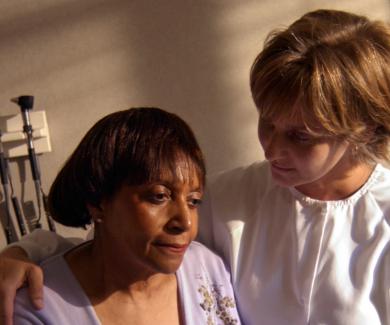 a doctor stands next to a patient's beside with her arm around the patient's soldier