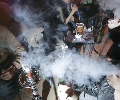 A group of young adults smoke in a hookah lounge. 