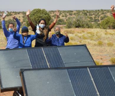 Navajo Nation residents cheer next to hydropanels