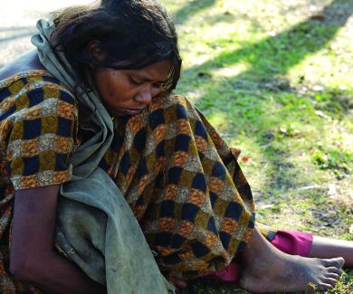 a woman sits on the ground with a blanket wrapped around her