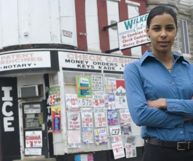 Sara Bleich stands in front of a corner store that abuts rowhomes in Baltimore