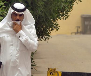 A Saudi man covers his mouth while walking down the street