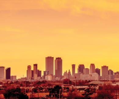 The summer sun sets over the skyline in New Orleans.