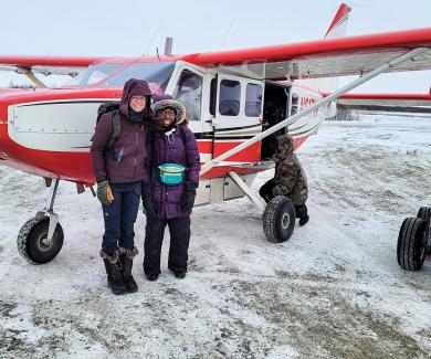 Mary McQuilkin and Bionca Davis in front of a plane in Alaska.