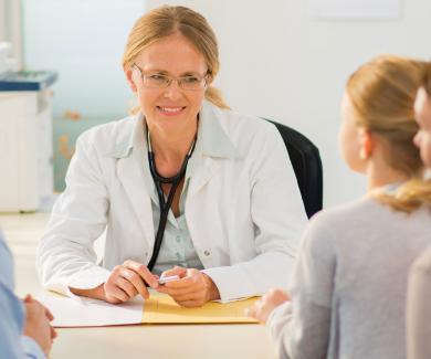 a female pediatrician talks with parents and their young daughter