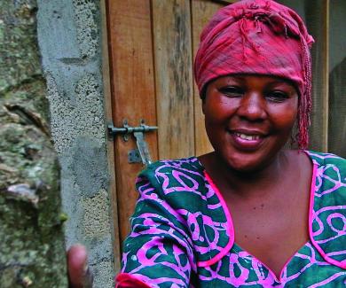 A Tanzanian woman in a colorful pink headscarf and blue and pink dress