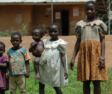 4 children standing in line youngest to oldest; one child holds a toddler on her hip.