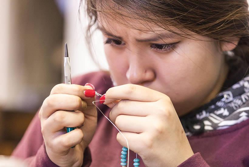 Alexis Hinton threads a beading needle