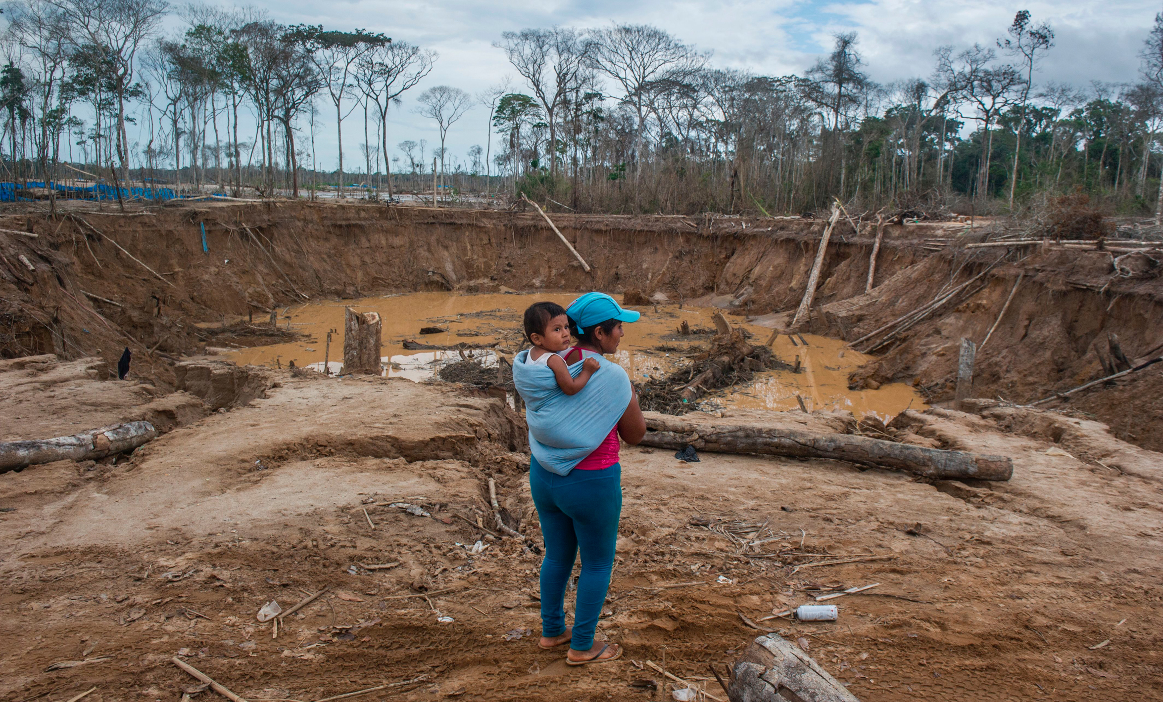 A local woman and her child stand in front of the remains of an illegal gold mining area of La Pampa, in the Madre de Dios southern Peruvian jungle, on July 14, 2015.